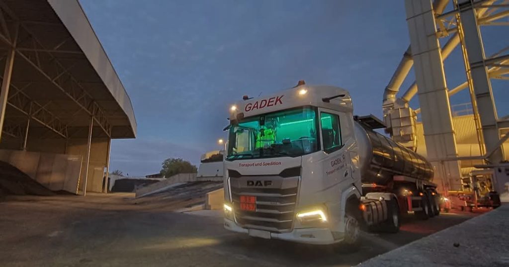 GADEK-Tankauflieger bereit zur Entladung im Industrieterminal bei Nacht – Einsatzbereitschaft und Professionalität.