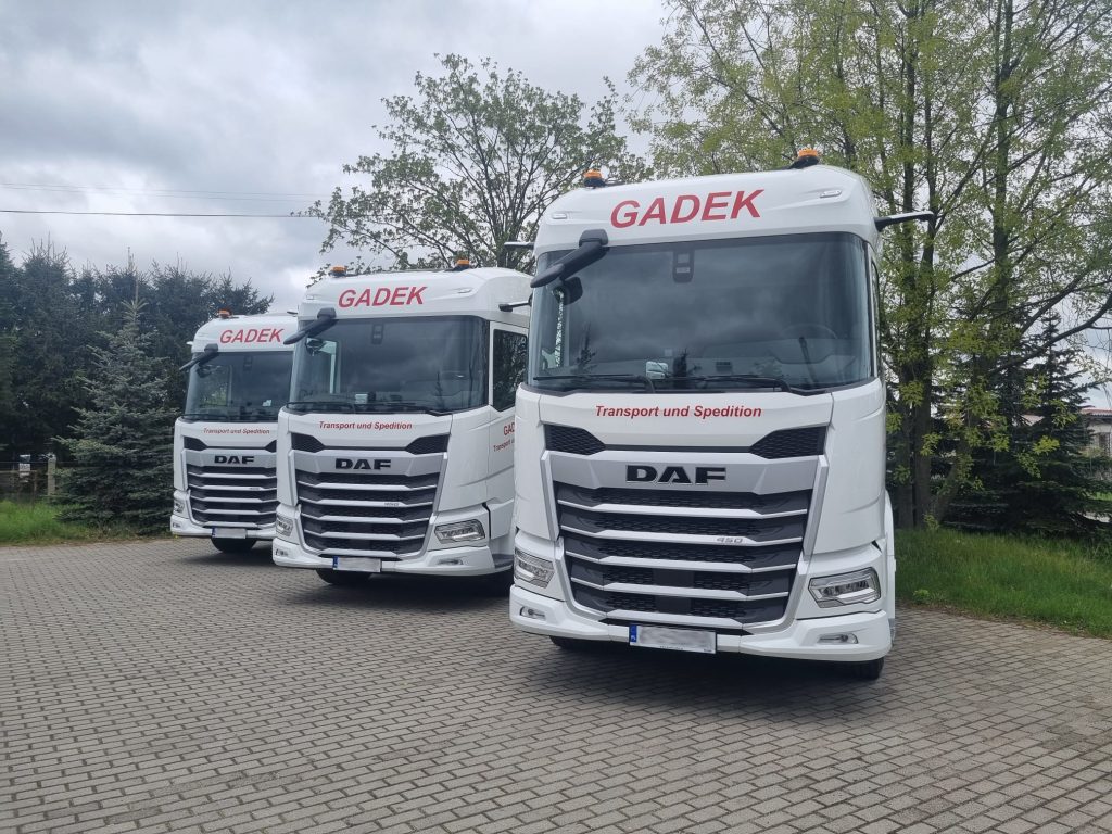 Drei Sattelzugmaschinen der Firma GADEK vor dem Betriebshof – moderne Transportflotte.